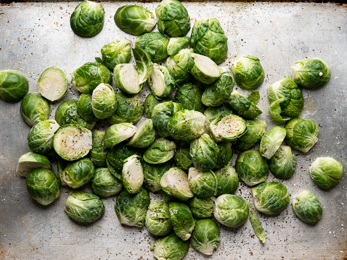 tossing brussels sprouts with olive oil on sheet pan