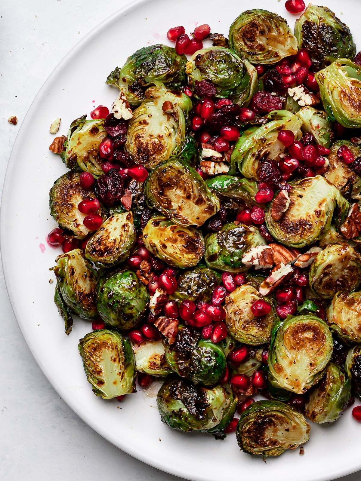 close up of Roasted Brussels sprouts tossed with pecans, pomegranate seeds and a balsamic glaze 