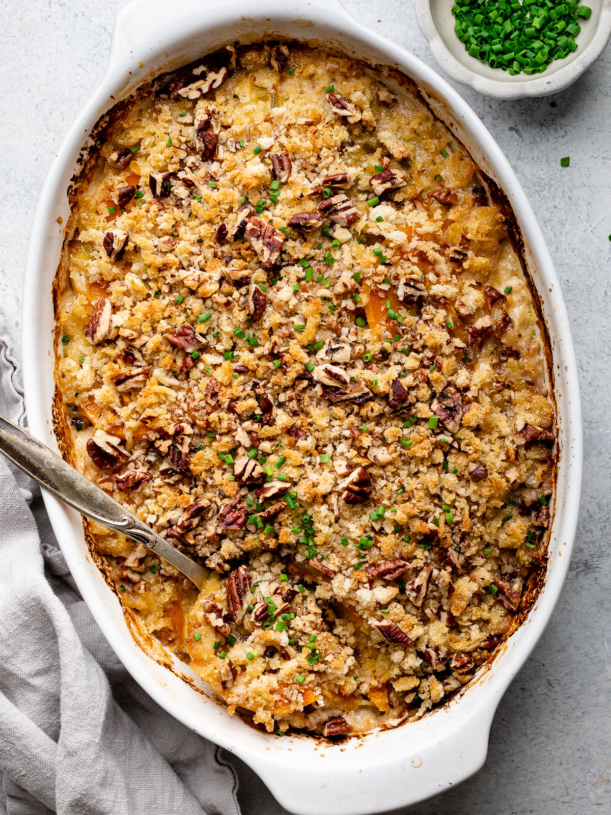 baked butternut squash gratin with small bowl of chives beside it