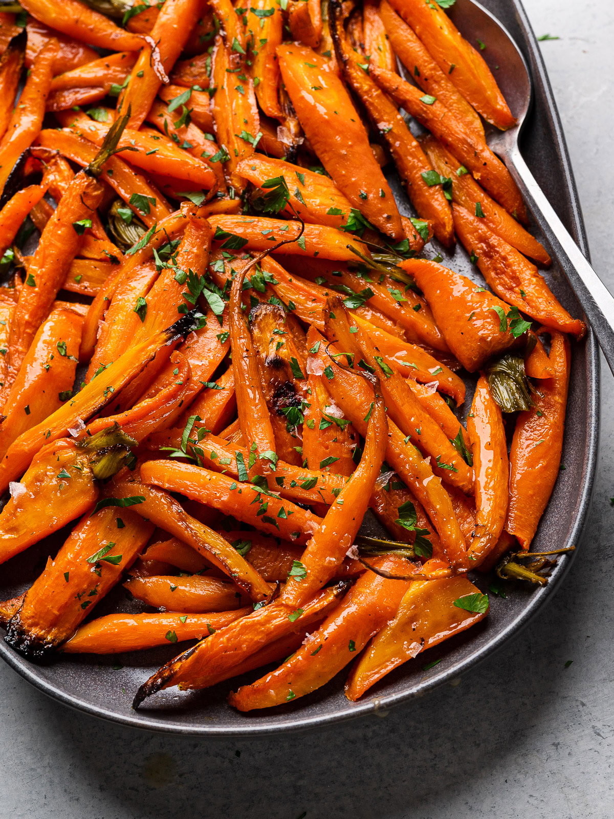 close up of Honey Maple Roasted Carrots served on platter garnished with parsley and flaky salt