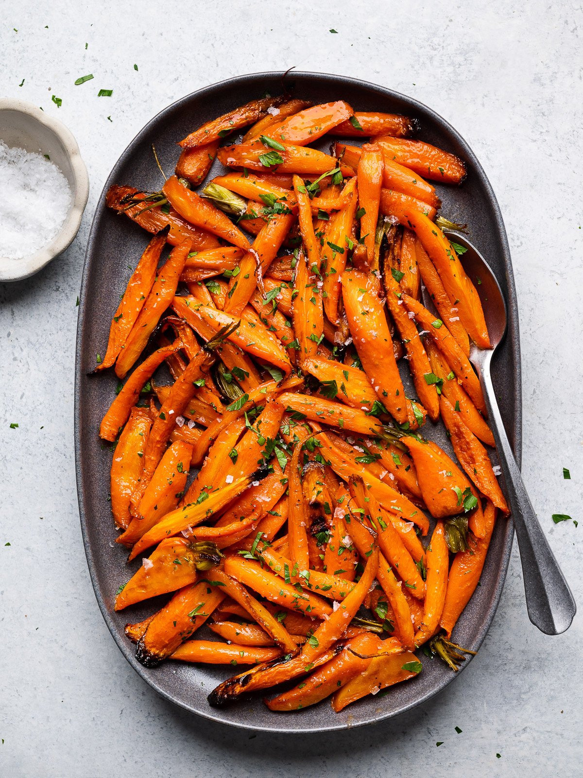 Honey Maple Roasted Carrots served on platter garnished with parsley and flaky salt