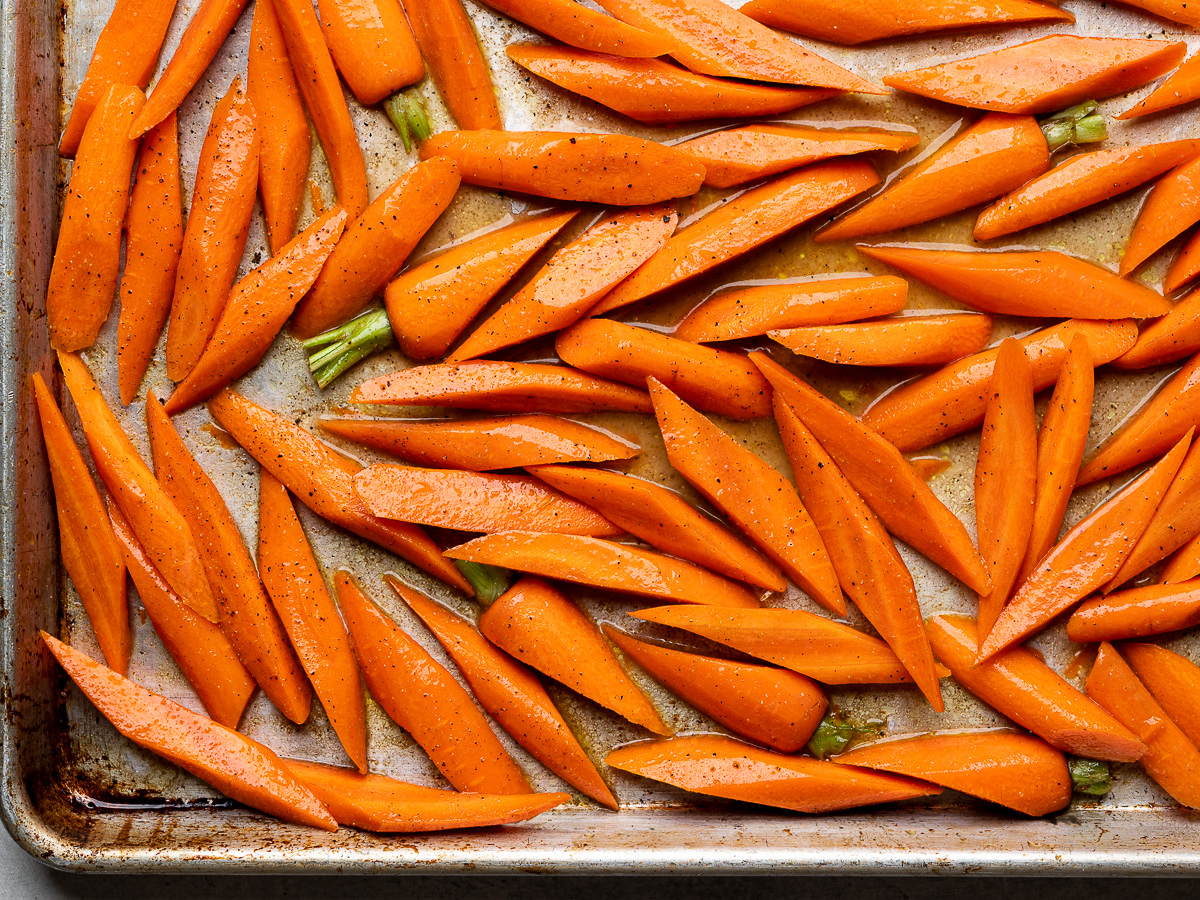 sliced carrots with glaze on baking sheet ready for roasting