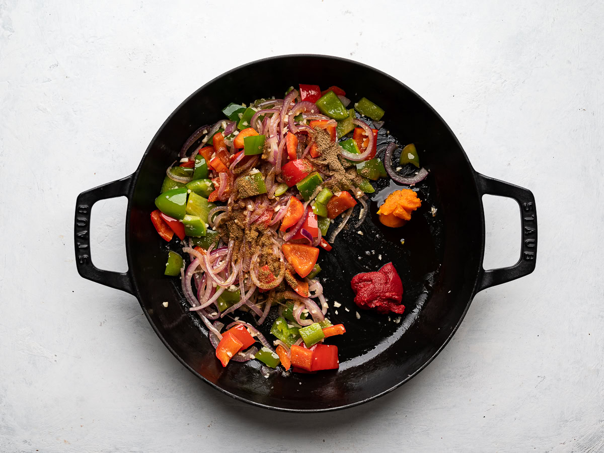 adding tomato paste and dende oil to skillet