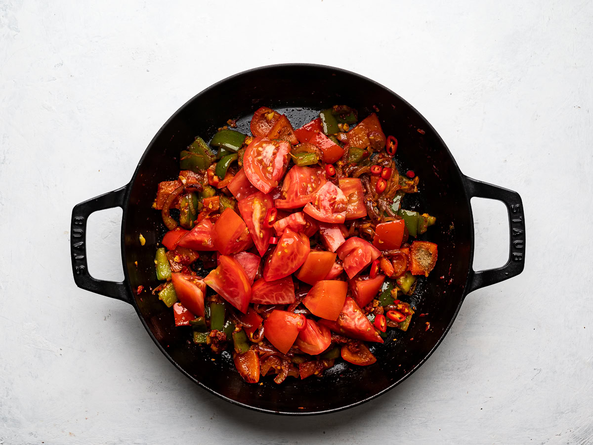 adding tomatoes to vegetable mixture