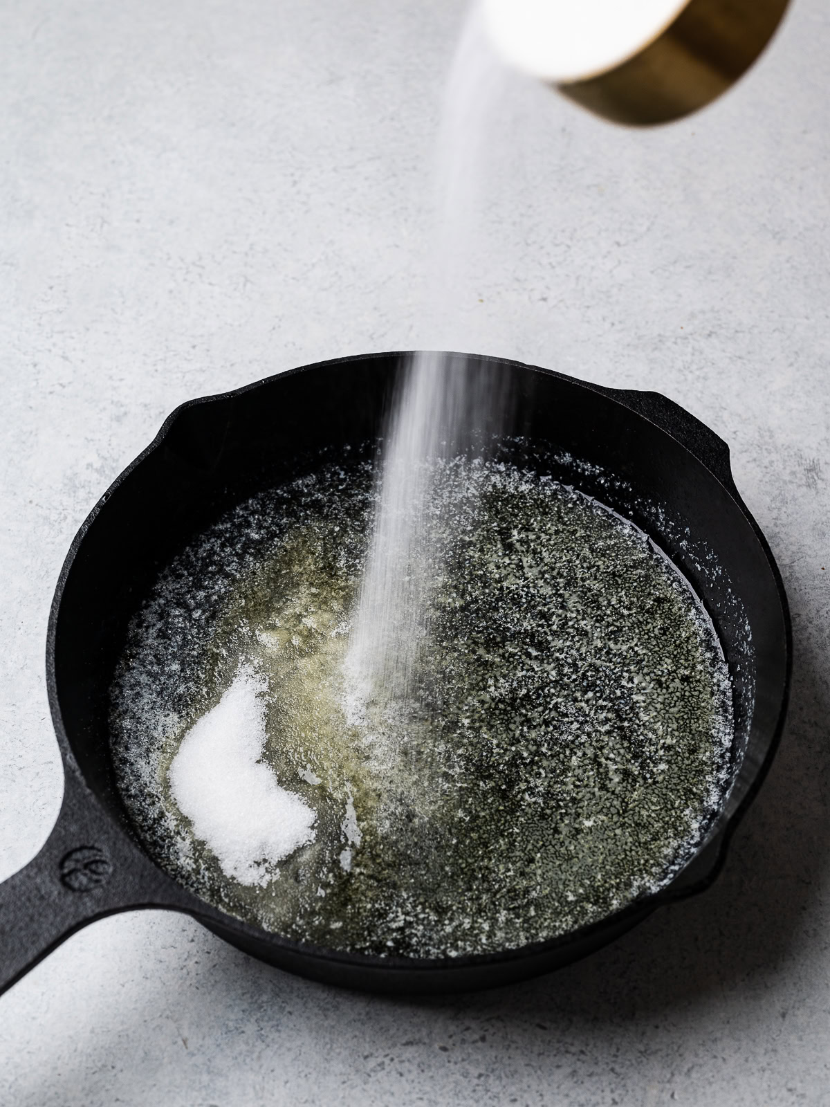 sprinkling sugar over melted butter in skillet