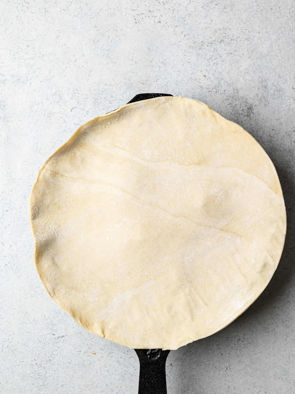 placing cold, rolled out puff pastry over apples