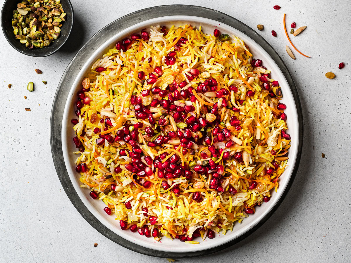 Persian style jewel rice served on platter with pistachio bowl on the side