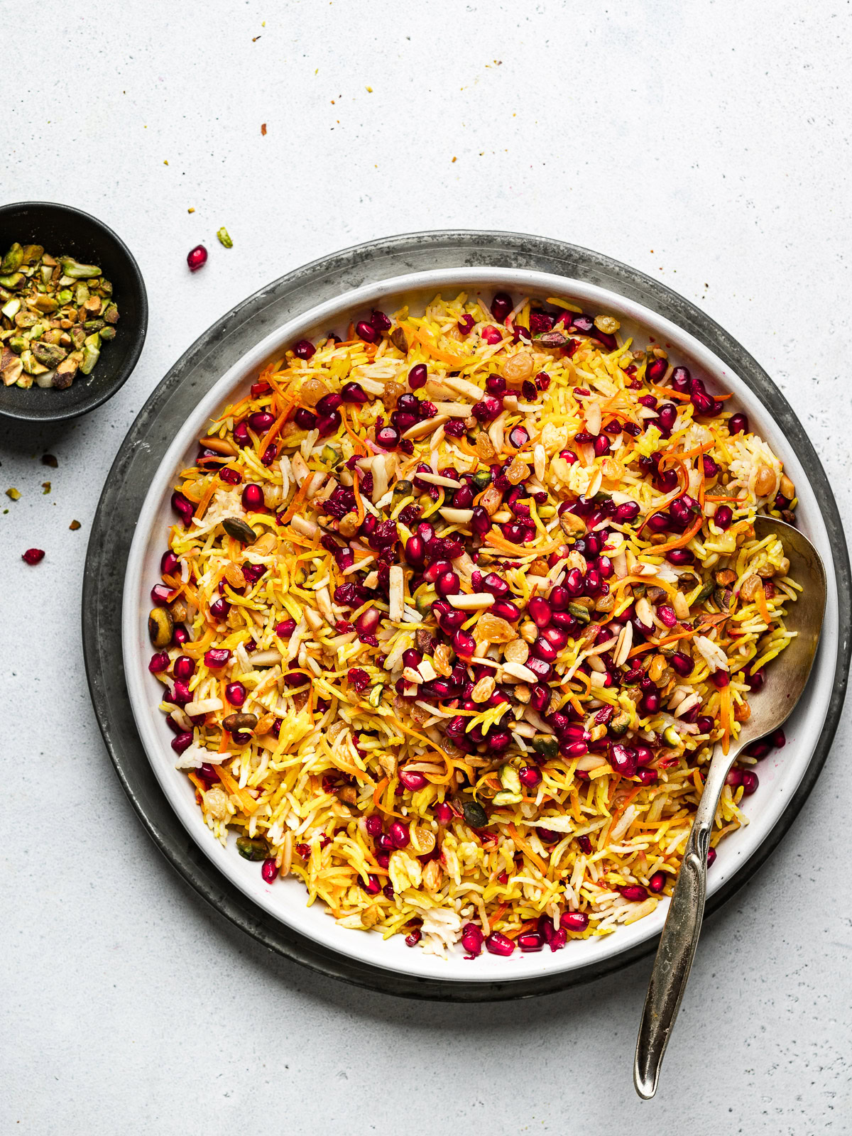 Persian style jewel rice served on platter with pistachio bowl on the side