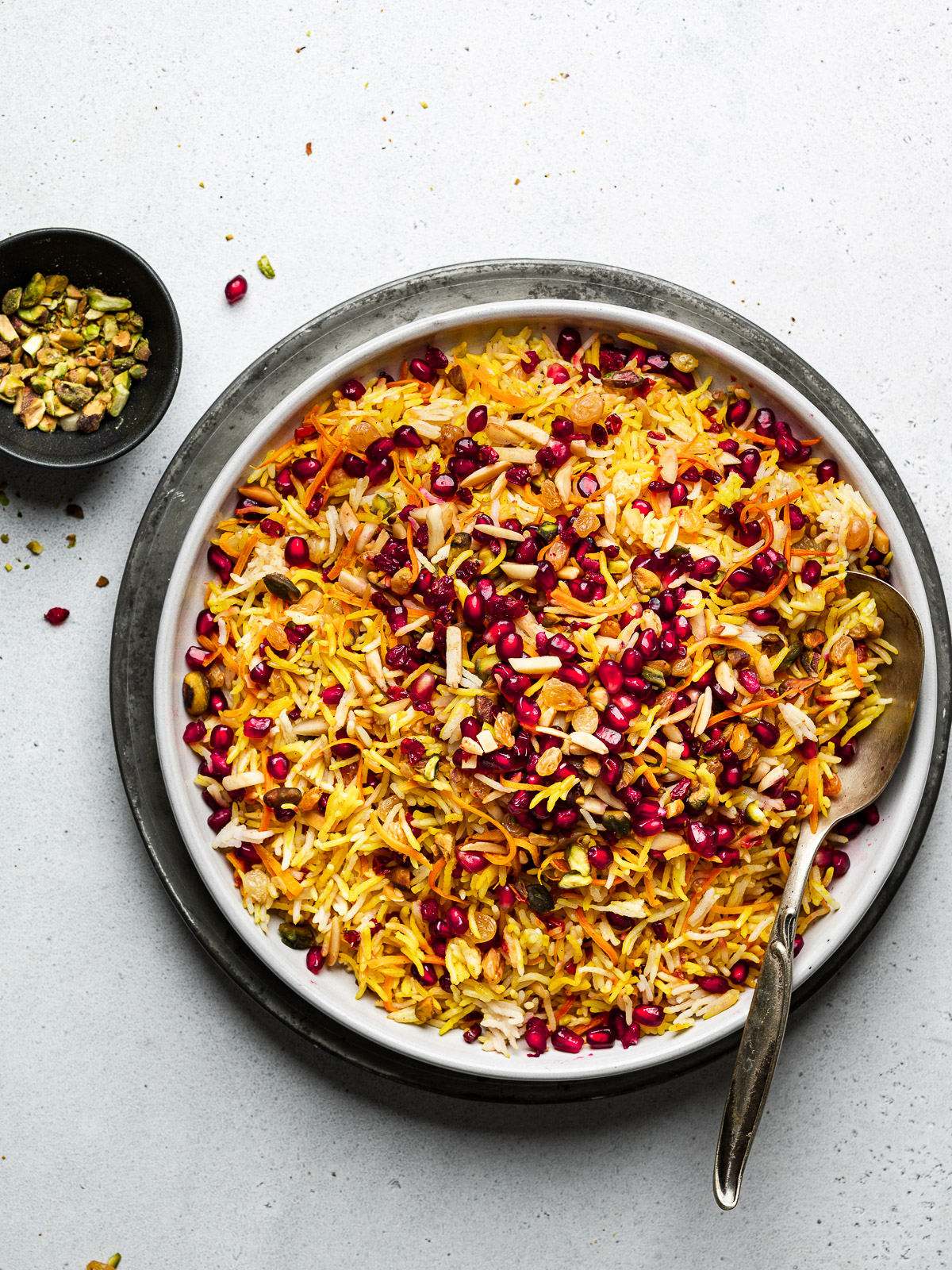 Persian style jewel rice served on platter with pistachio bowl on the side