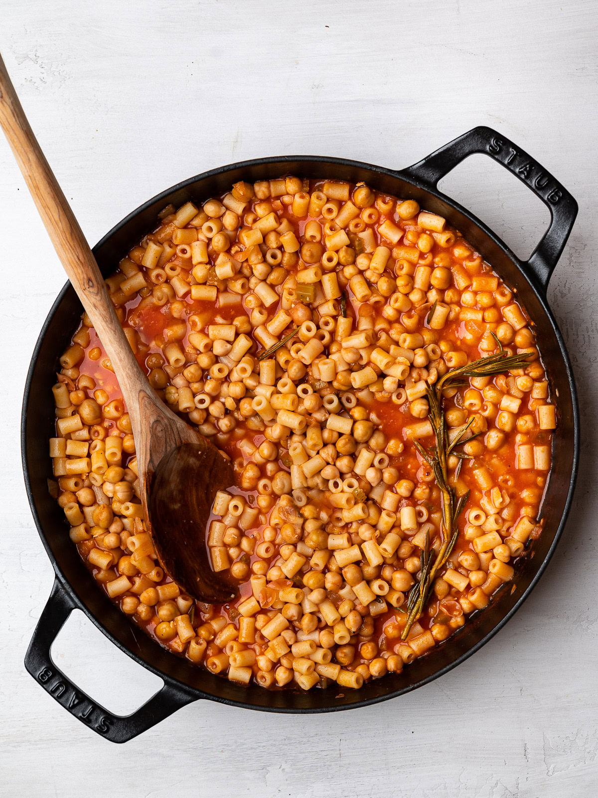 cooked pasta and chickpeas in skillet with wooden spoon