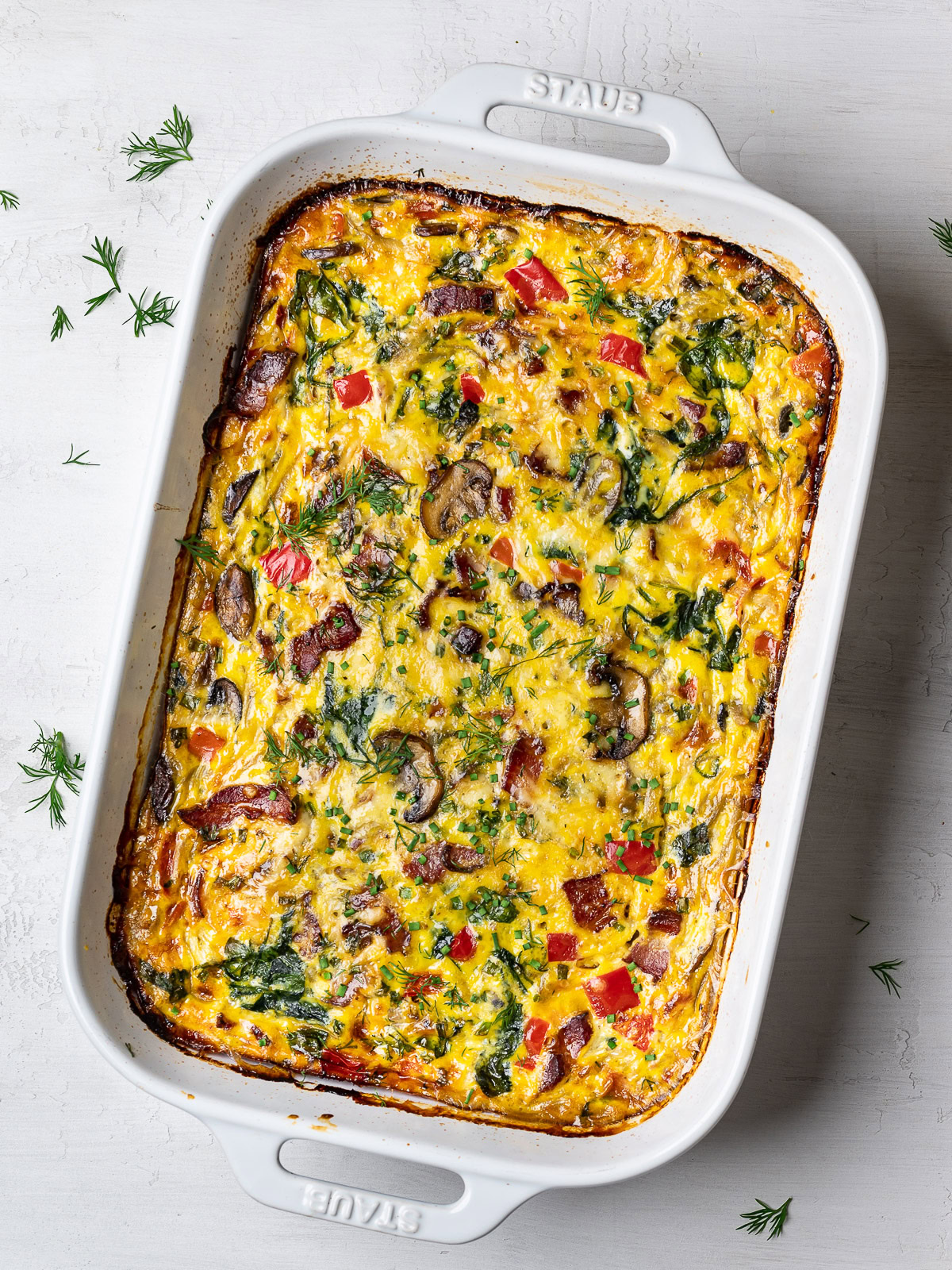 baked breakfast casserole garnished with dill and chives