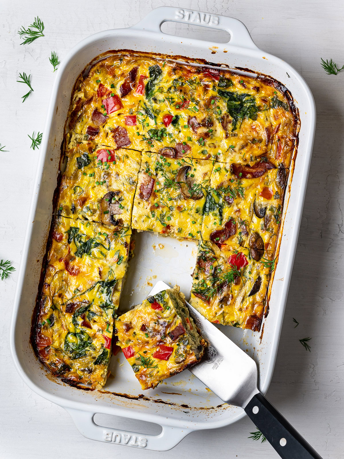 sliced breakfast casserole garnished with dill and chives