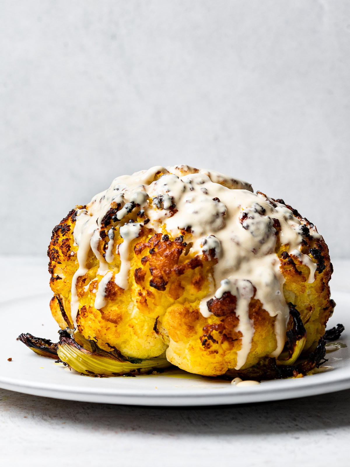 side-view of roasted cauliflower drizzled with tahini sauce