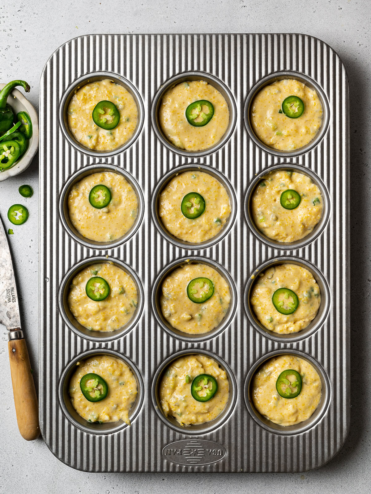 garnishing muffins with jalapeño slices