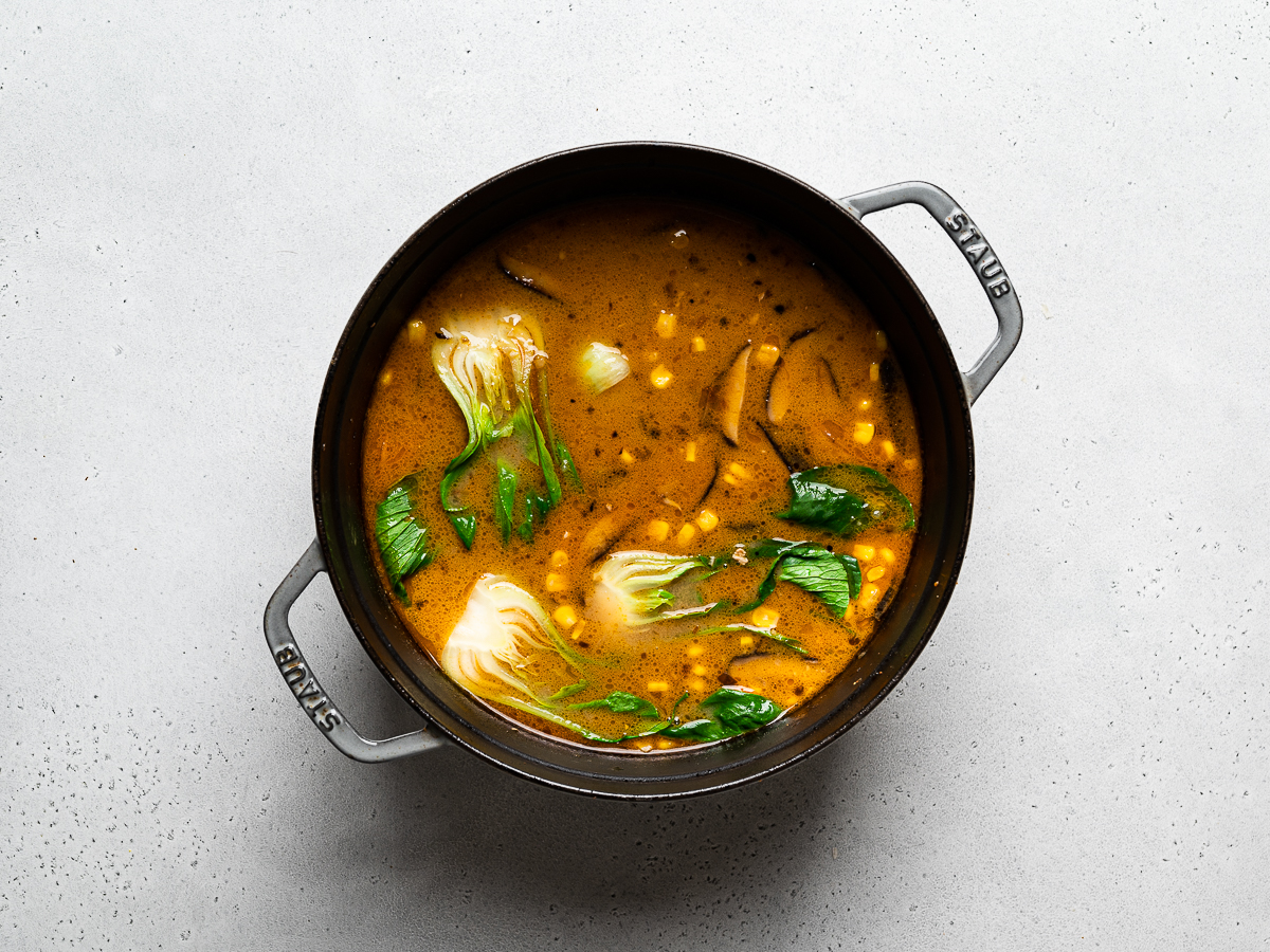broth simmering in pot with corn and bok choy
