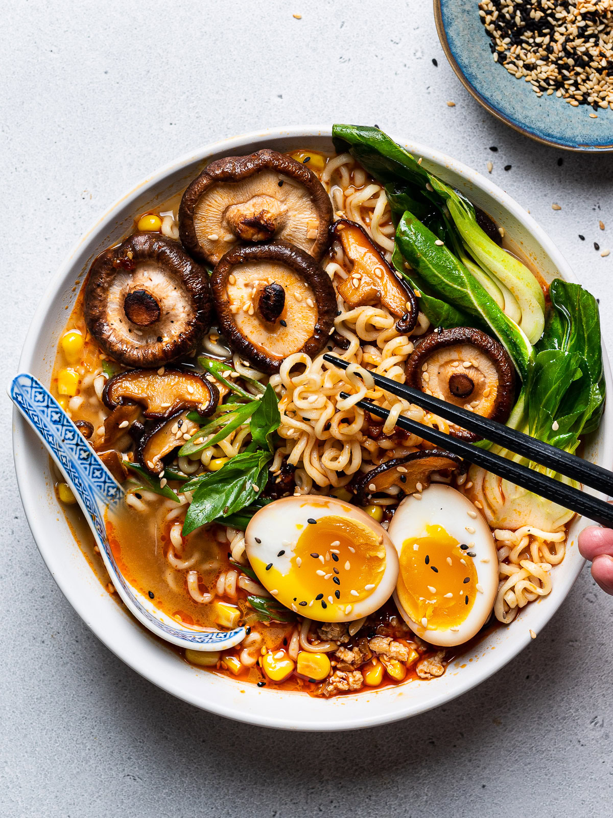 spicy miso ramen served in bowl with soy sauce eggs and chopsticks fishing out some noodles