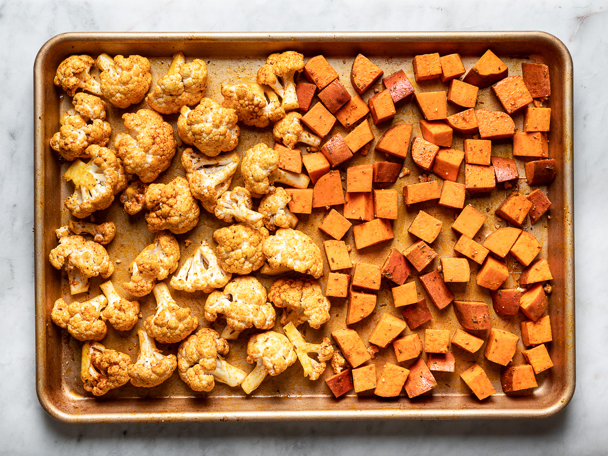 cauliflower and sweet potatoes on sheet pan before roasting