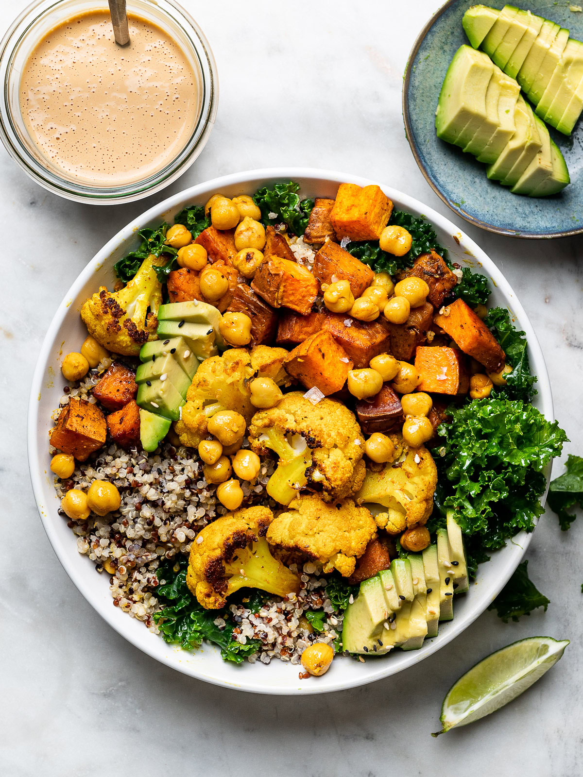 Buddha Bowl with Roasted Veggies with spicy cashew sauce and avocado slices on the side