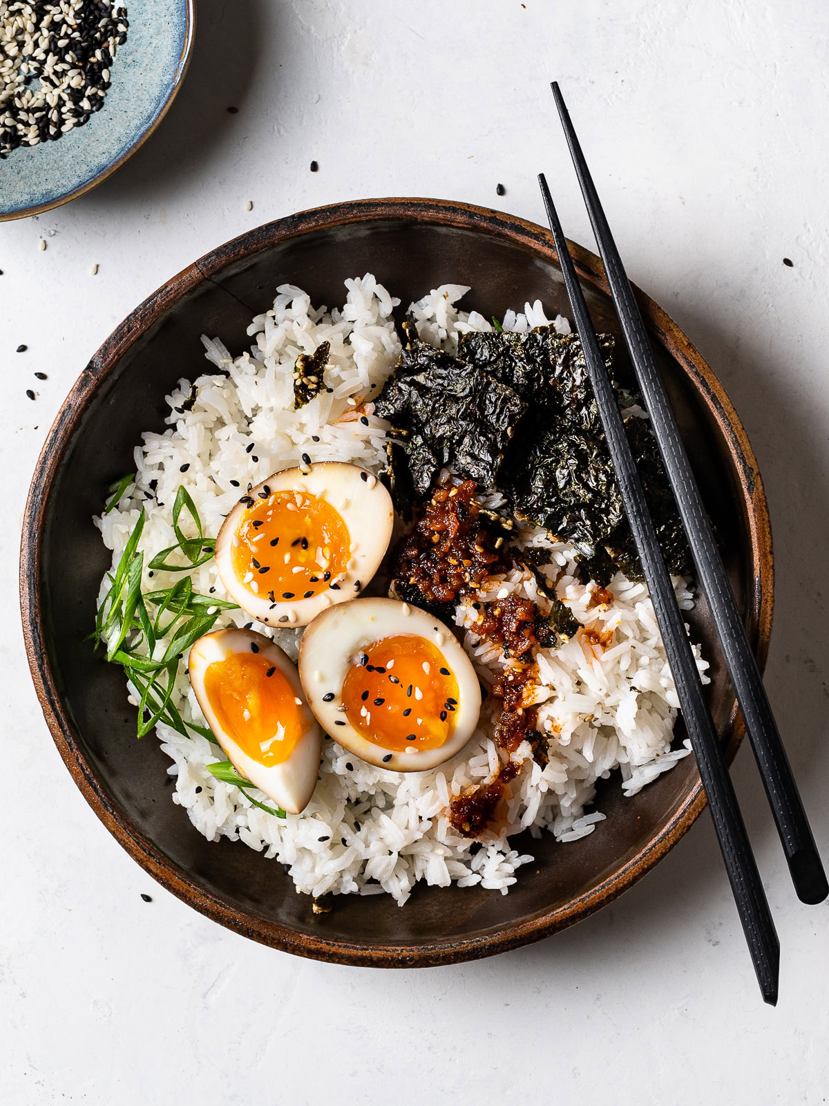 top-view of soy sauce eggs topping white rice in a bowl