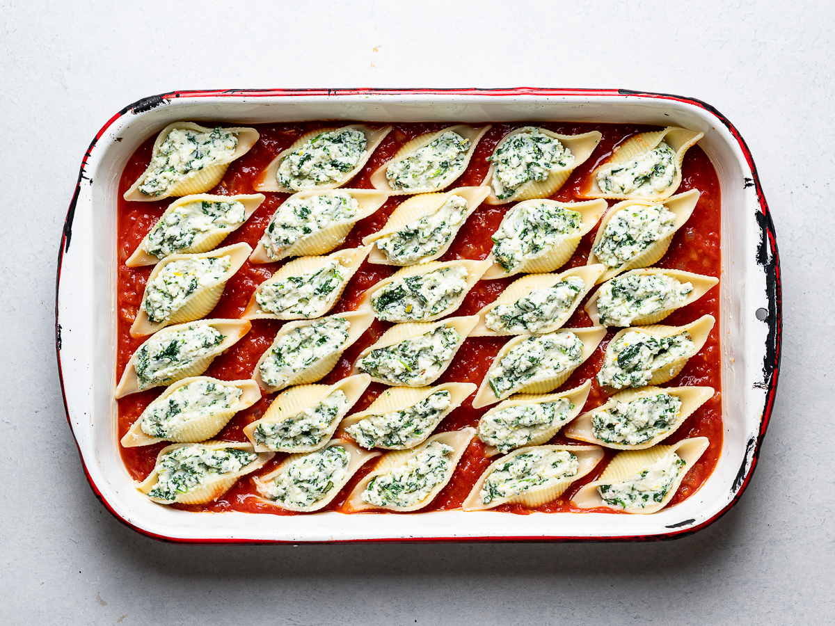 stuffed shells ready to be baked in baking dish with tomato sauce