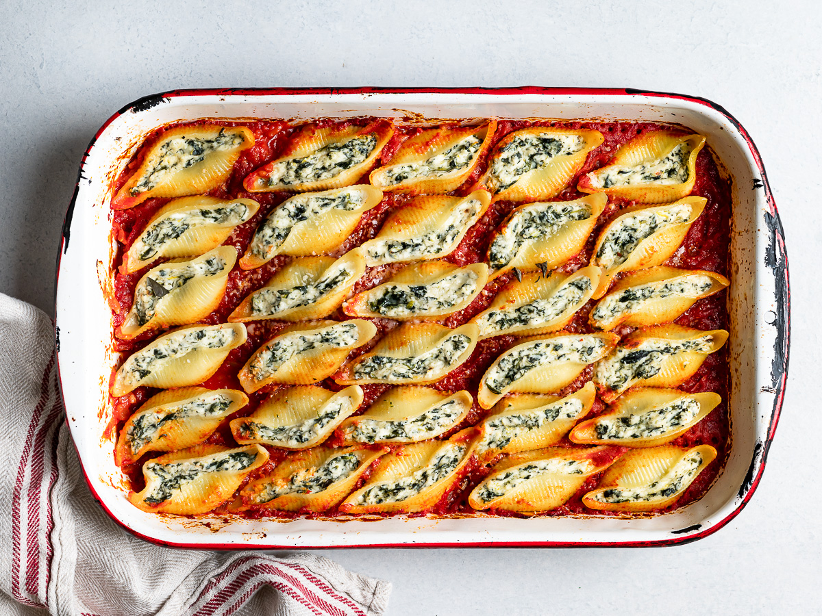 baked stuffed shells in baking dish with tomato sauce 