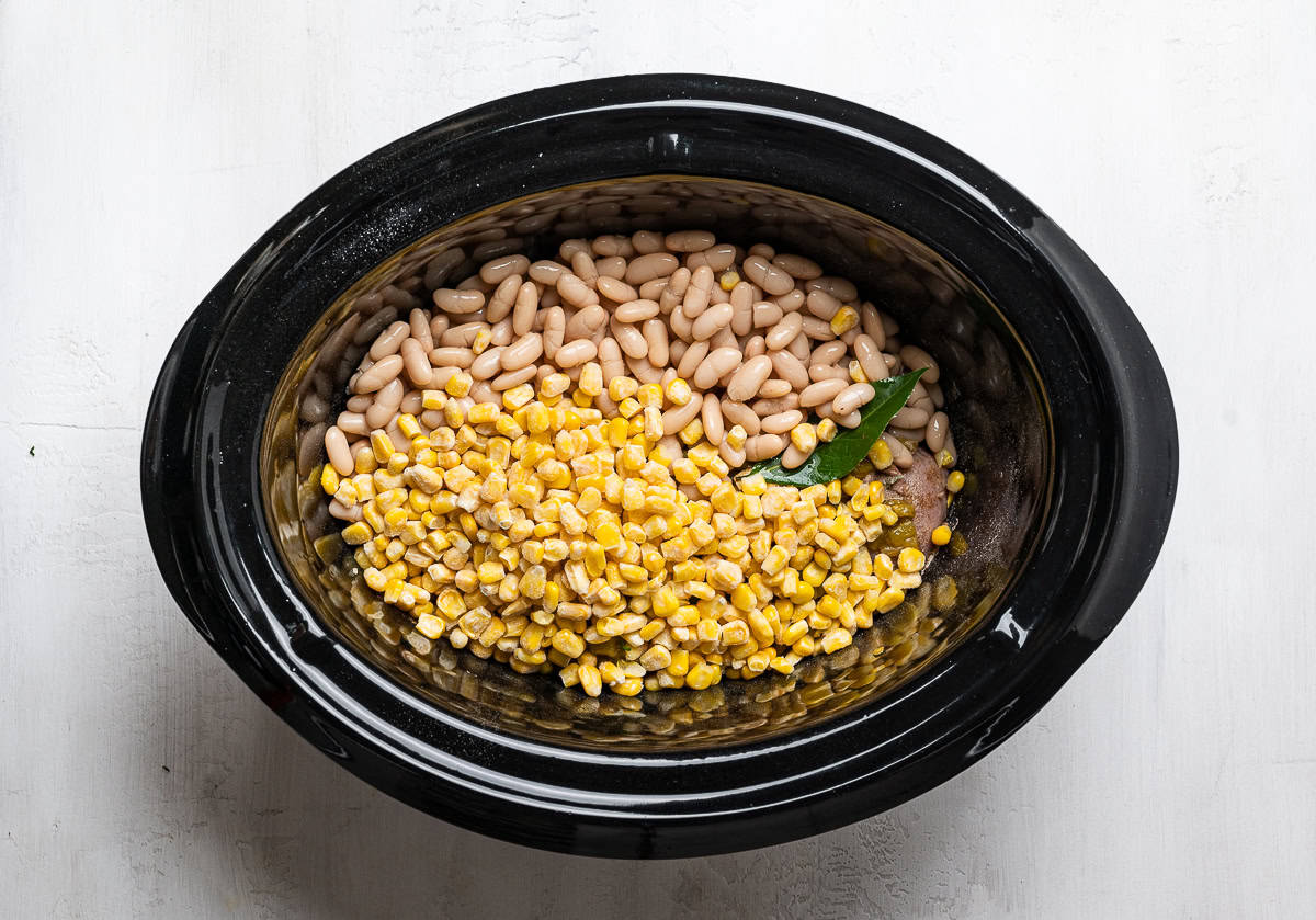 adding beans and corn to the slow cooker