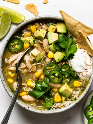 slow cooker white chicken chili served in bowl with toppings and tortillas