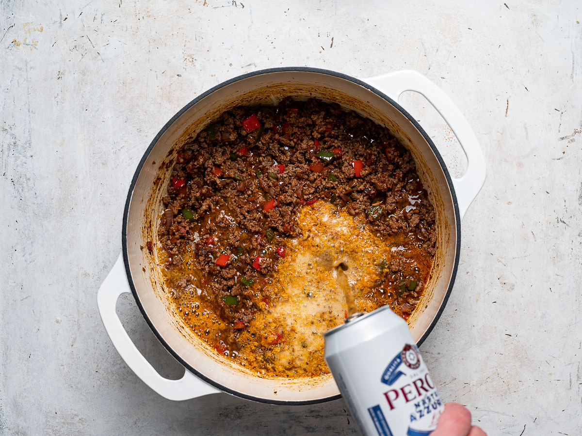 pouring beer into pot with beef and veggies