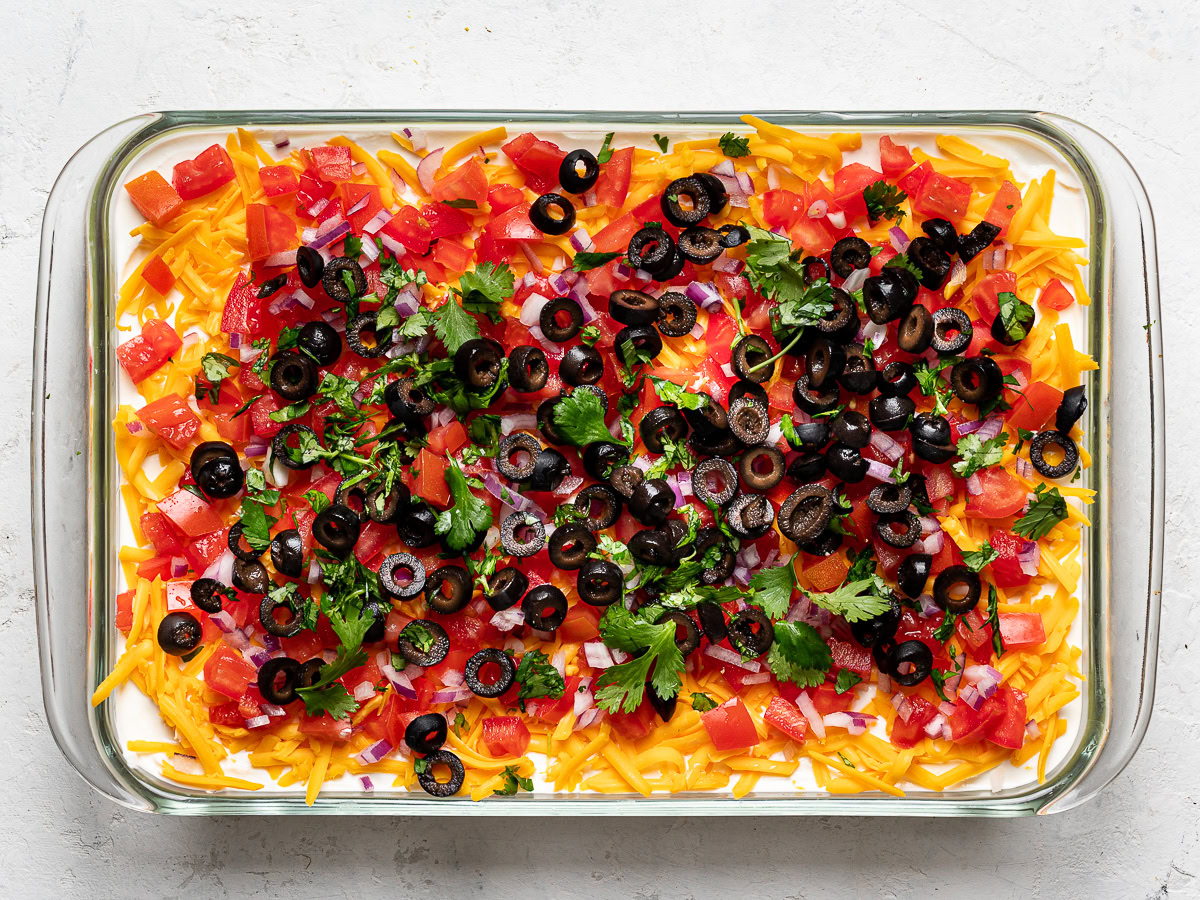 layer of tomatoes topped with black olives, red onions, and cilantro