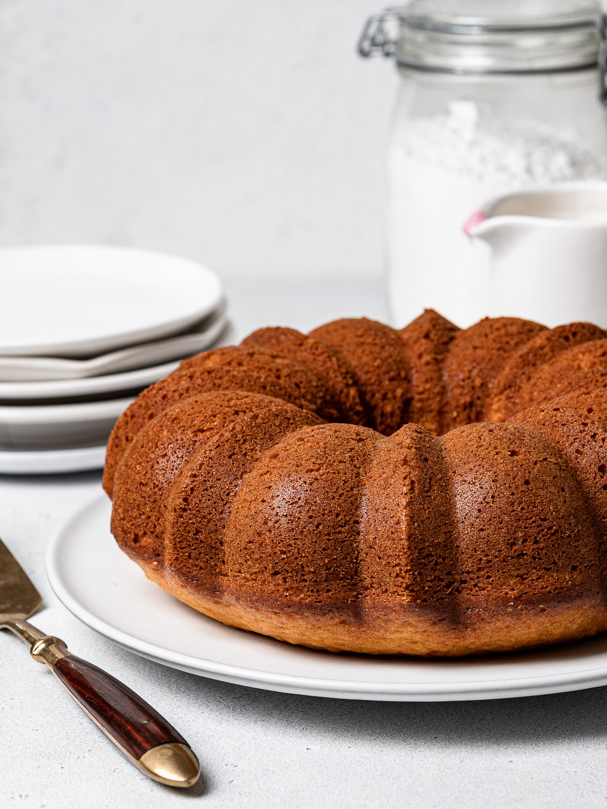 Side view of Bundt Cake without glaze with plates and bottles in background