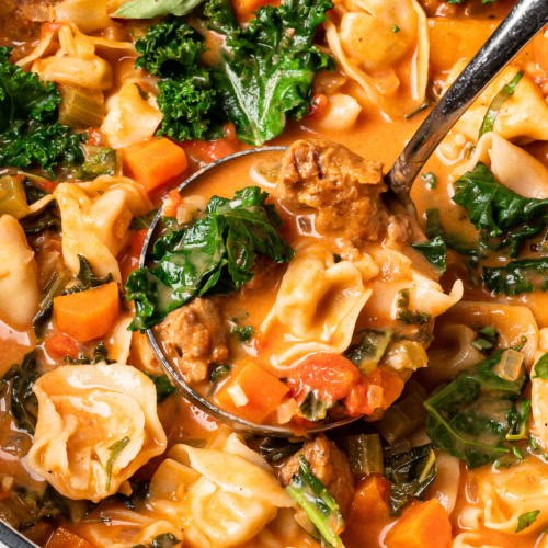 close up of a ladle filled with tortellini soup
