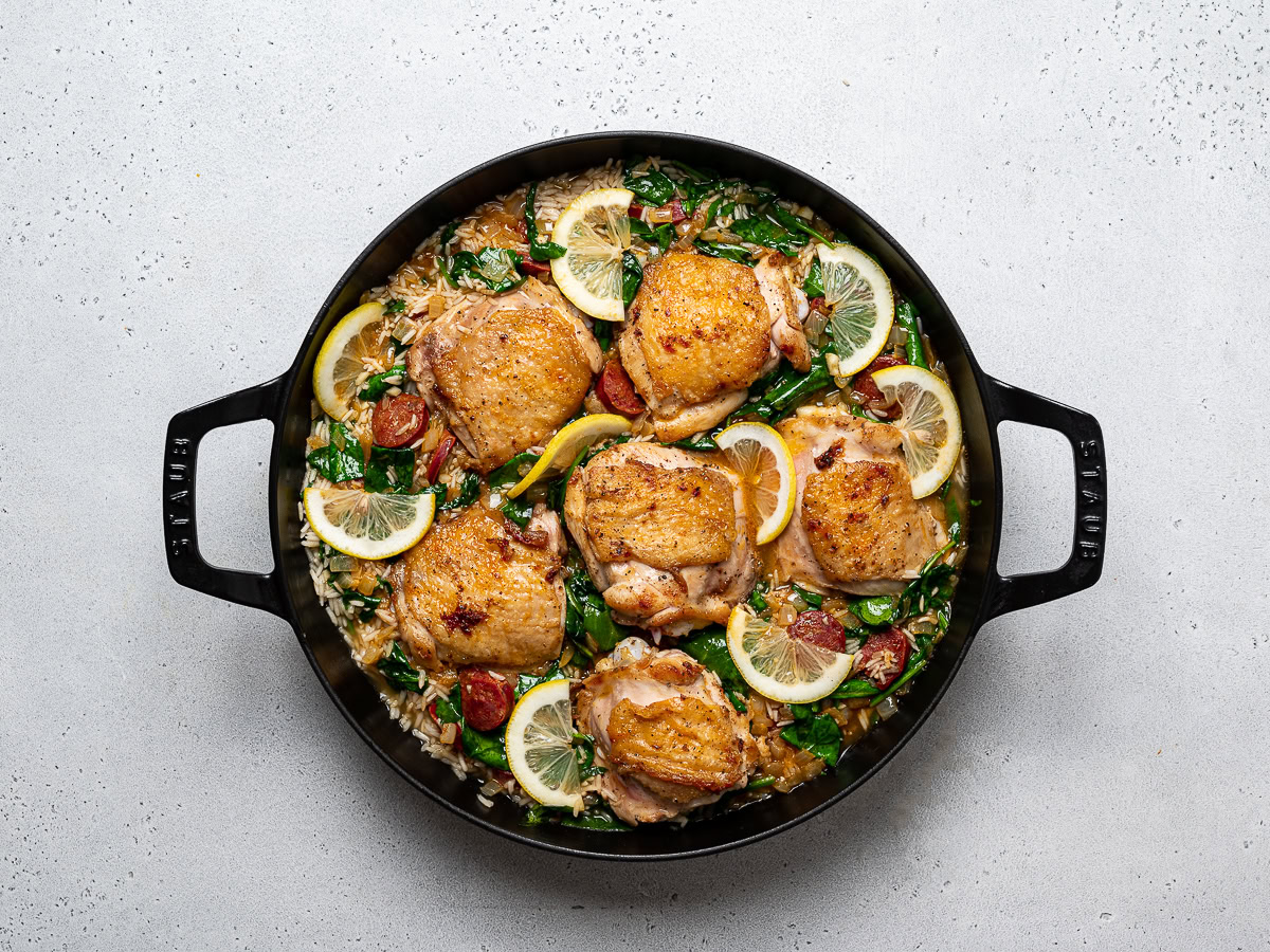 skillet with chicken, rice and all other ingredients ready to be baked