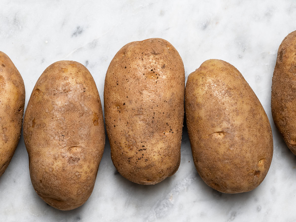 3 Russet potatoes lined up before baking