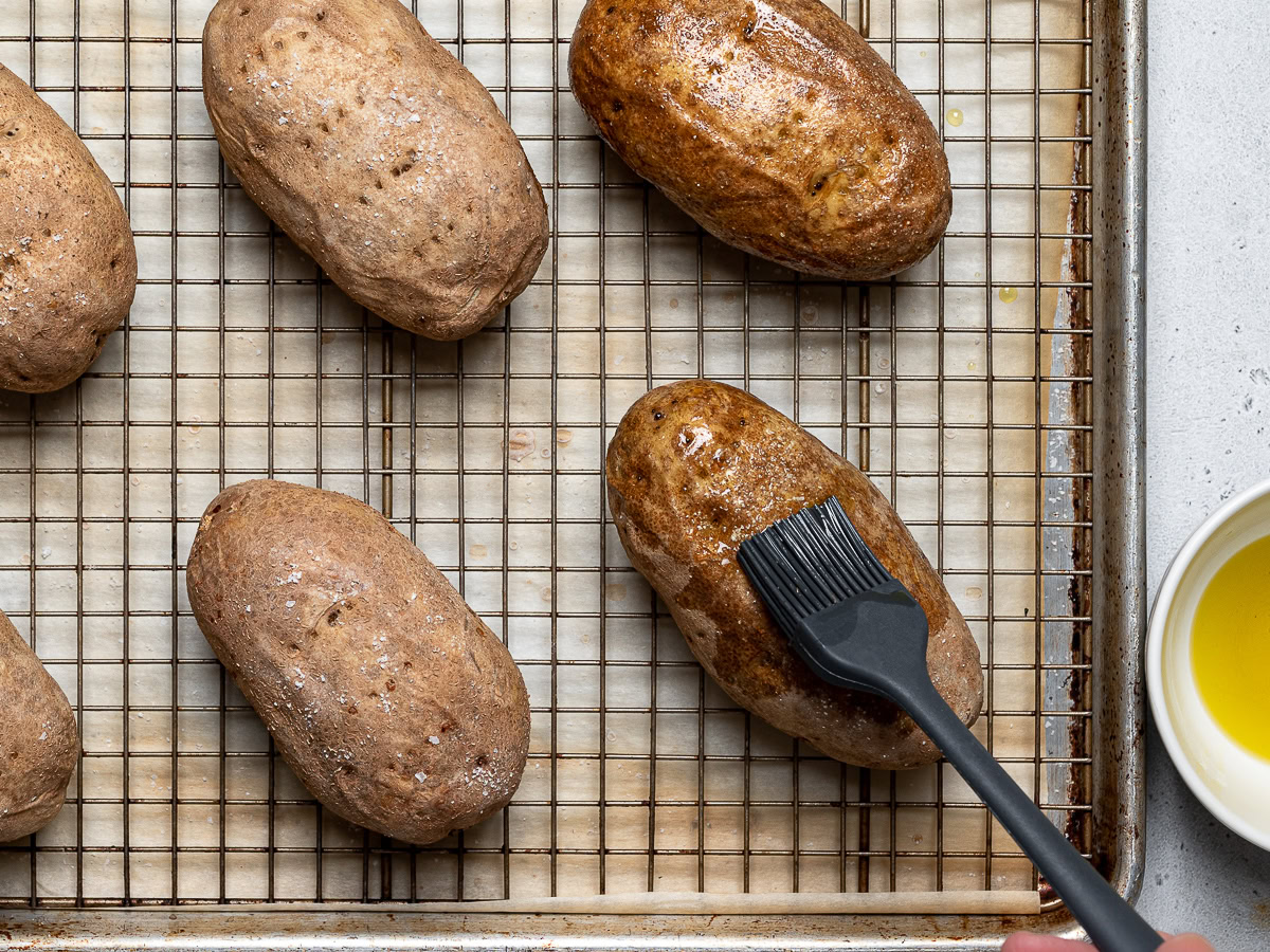 brushing oil on partially baked potatoes