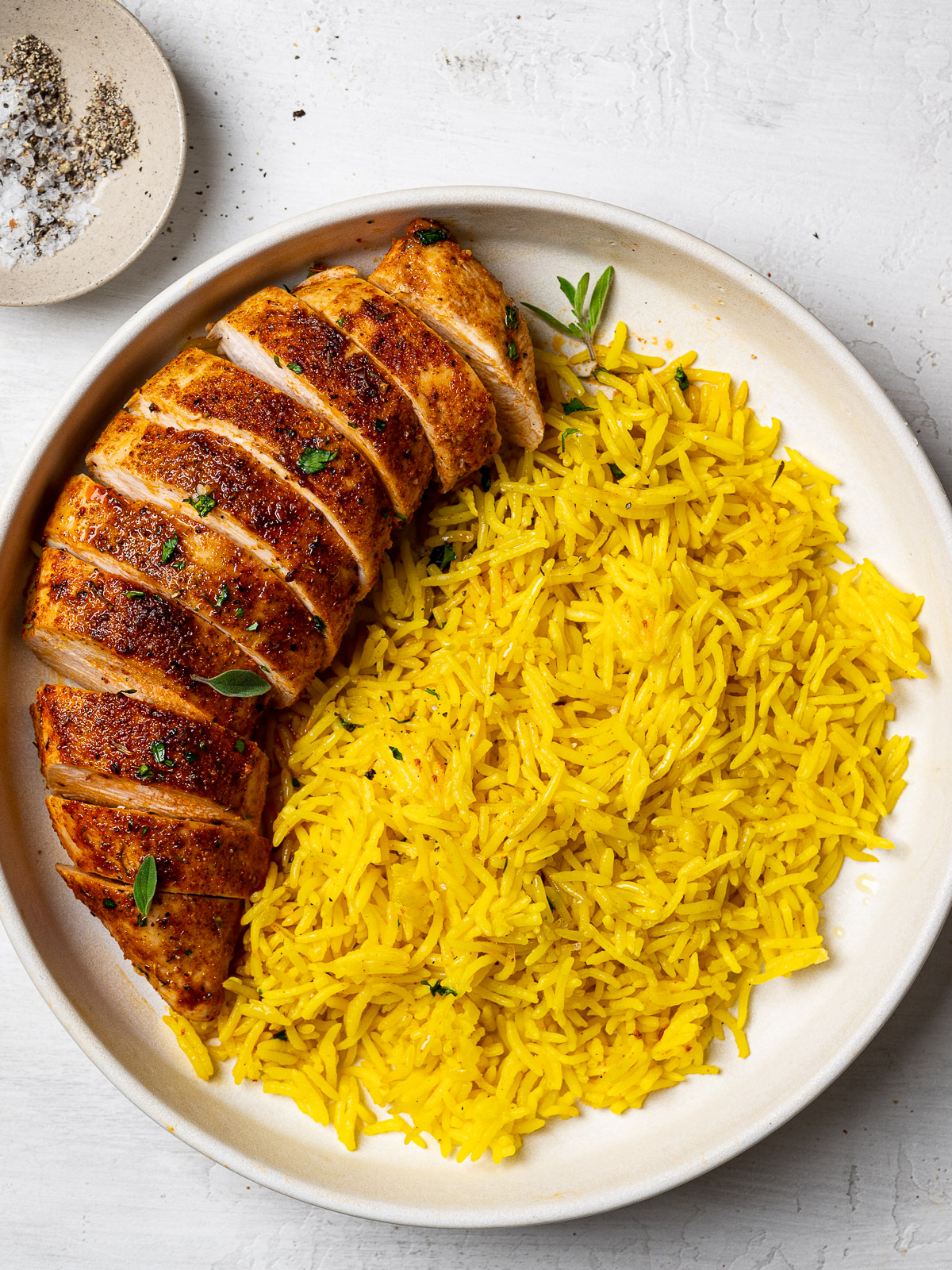 sliced chicken served on a plate with yellow rice