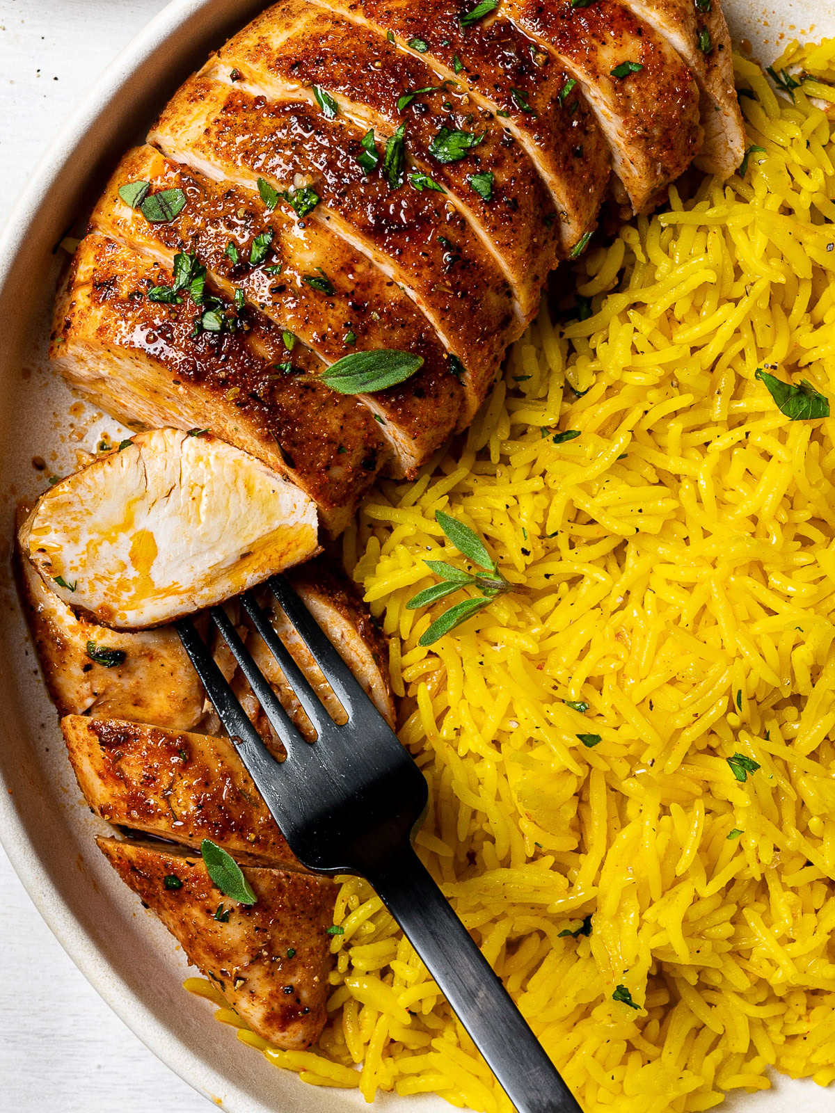 close up of fork holding sliced chicken piece 