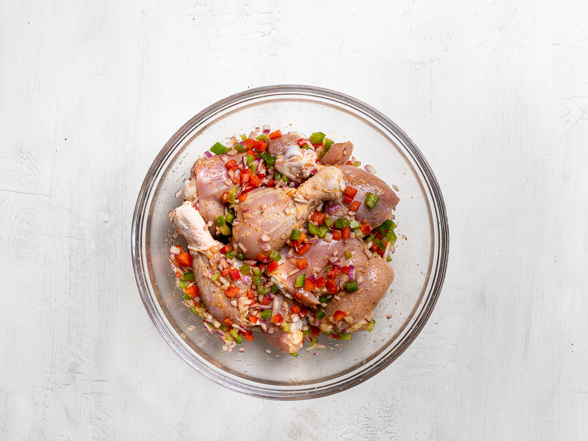 chicken pieces in glass mixing bowl tossed with marinade mixture