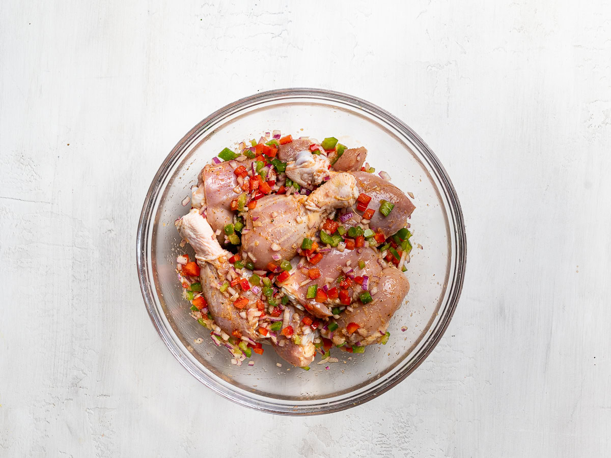 chicken pieces in glass mixing bowl tossed with marinade mixture