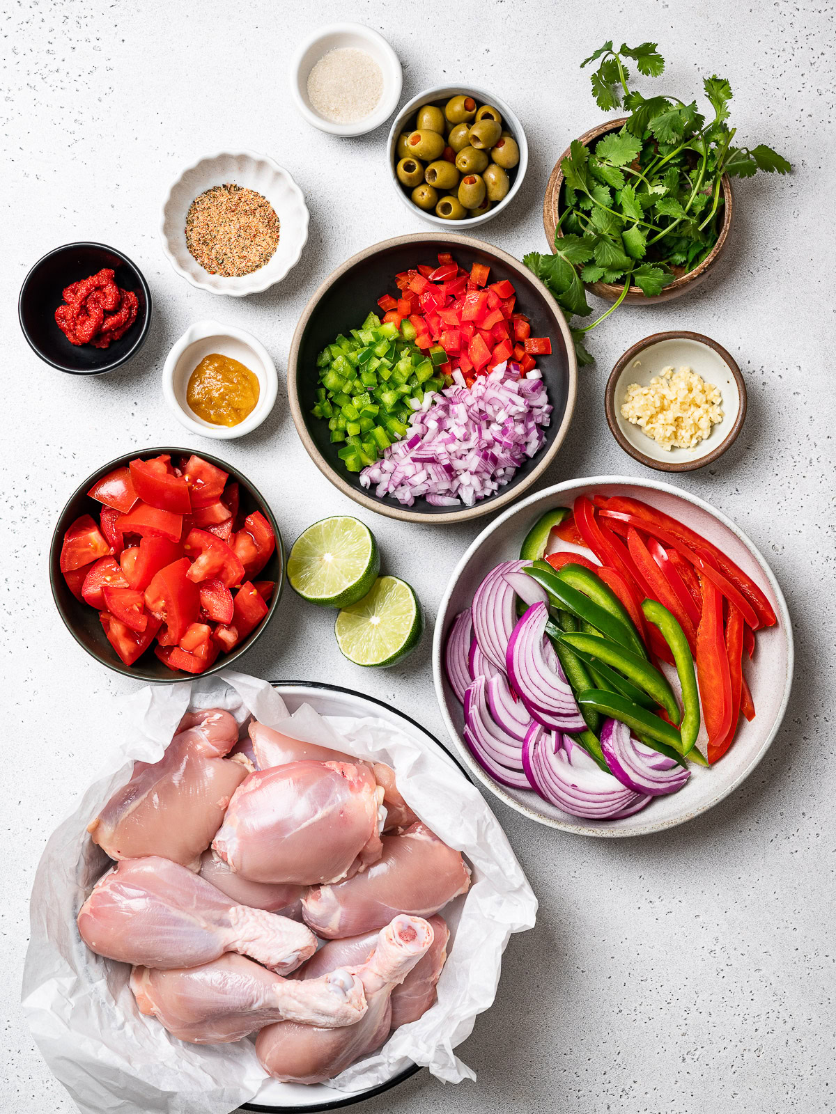 ingredients set out in small bowls to make pollo guisado recipe