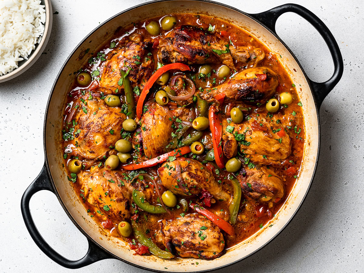 cooked pollo guisado in skillet with olives and chopped cilantro added