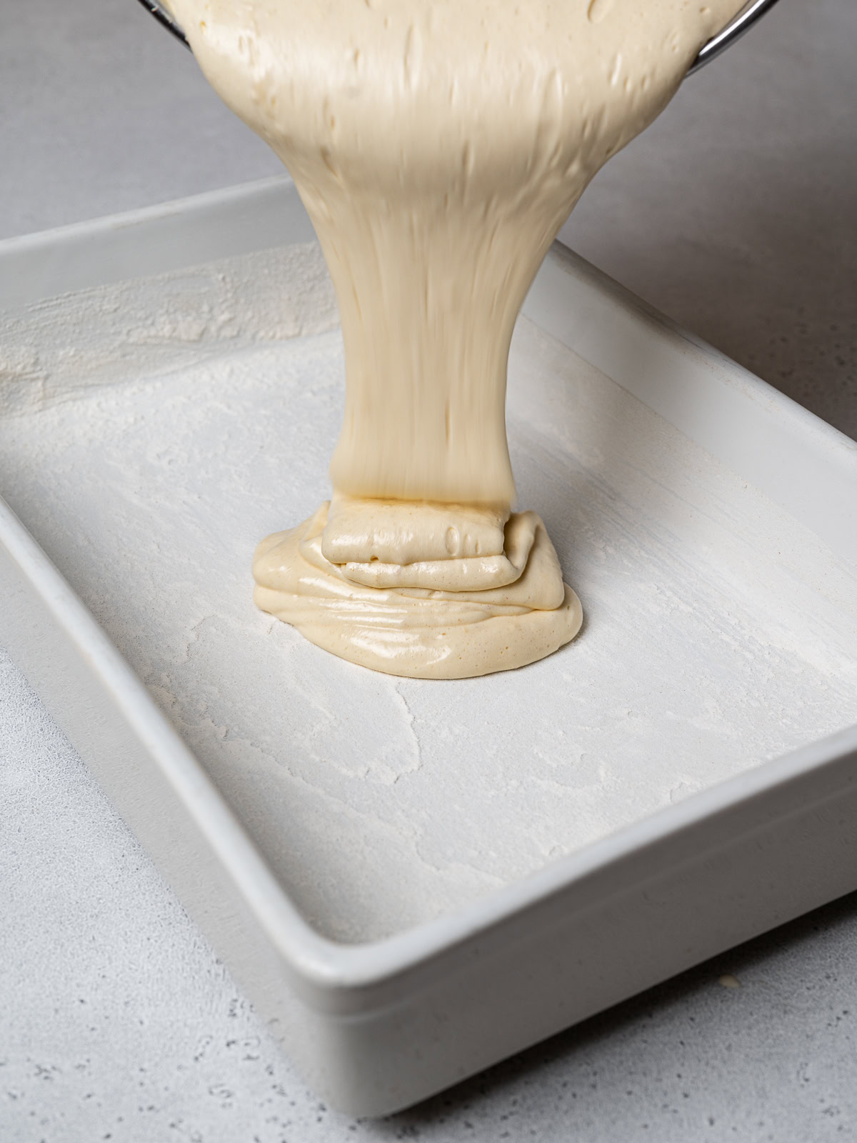 pouring sponge cake batter into greased baking dish