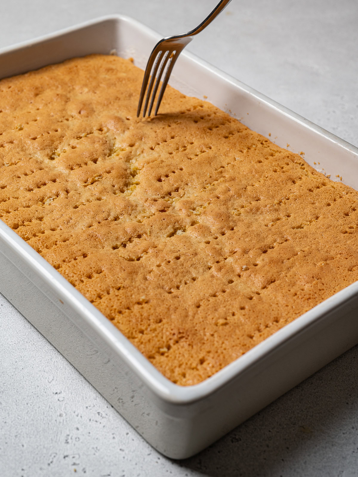 pricking holes with a fork all over the baked sponge cake