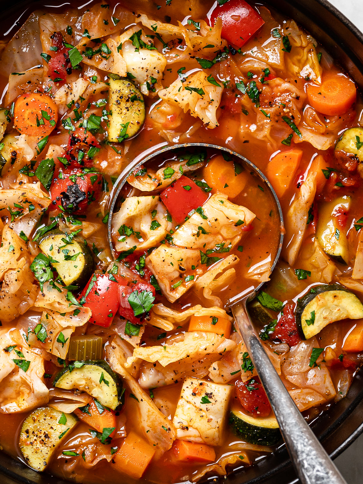 close up of cabbage soup in pot with ladle scooping out a serving