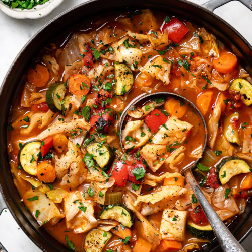 cabbage soup in pot with ladle scooping out a serving