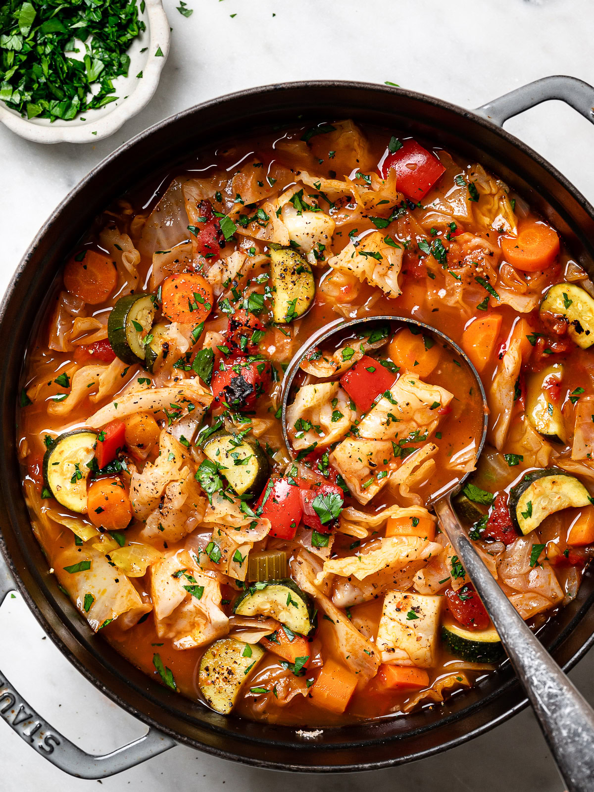 cabbage soup in pot with ladle scooping out a serving