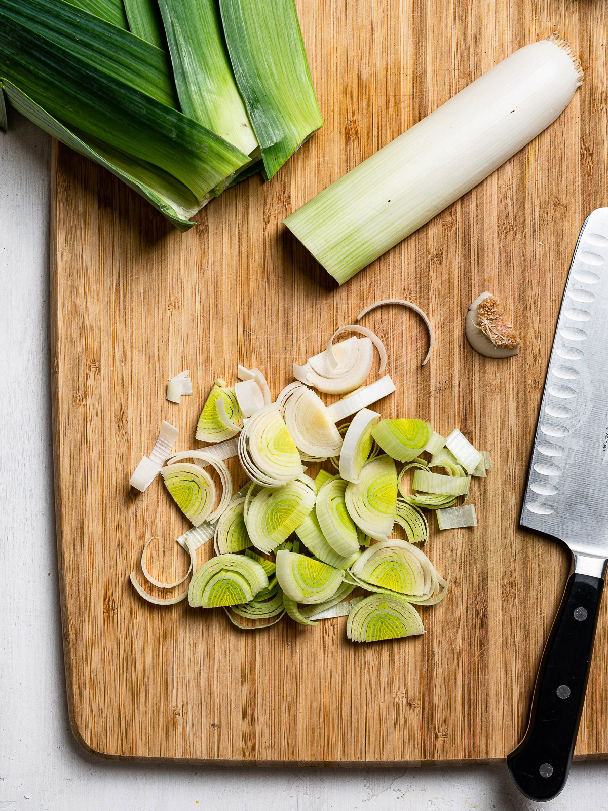 chopping leeks into half-moons on cutting board