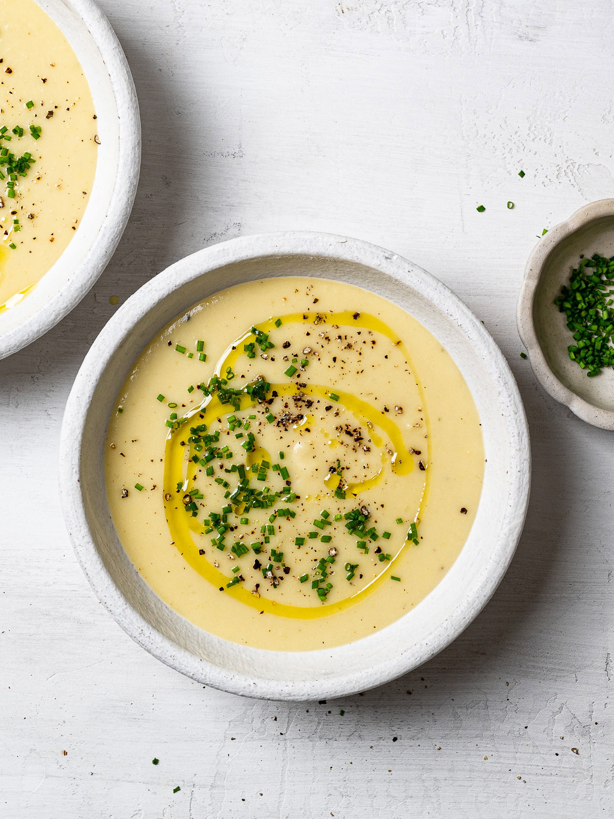 potato leek soup served in individual bowls garnished with chopped chives and freshly cracked black pepper