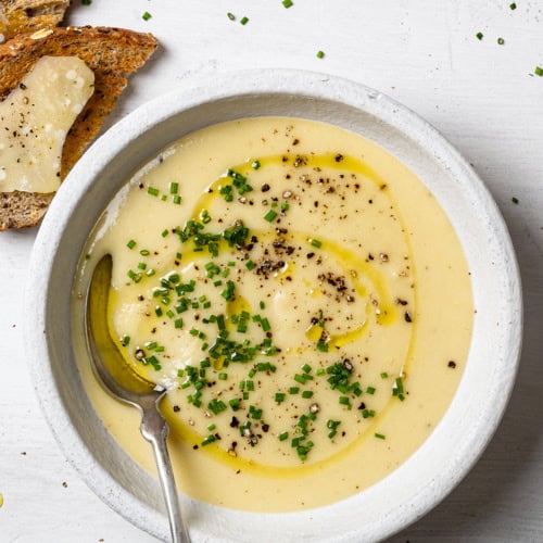 potato leek soup served in individual bowl garnished with chopped chives and freshly cracked black pepper