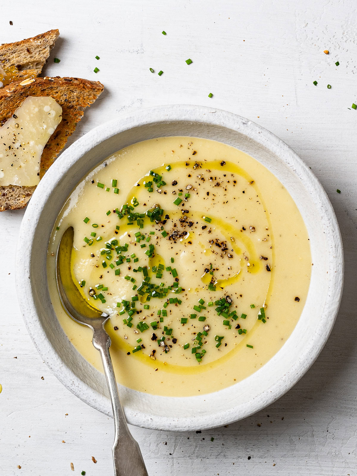 potato leek soup served in individual bowl garnished with chopped chives and freshly cracked black pepper