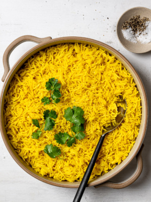 turmeric rice pilaf in serving bowl garnished with cilantro leaves